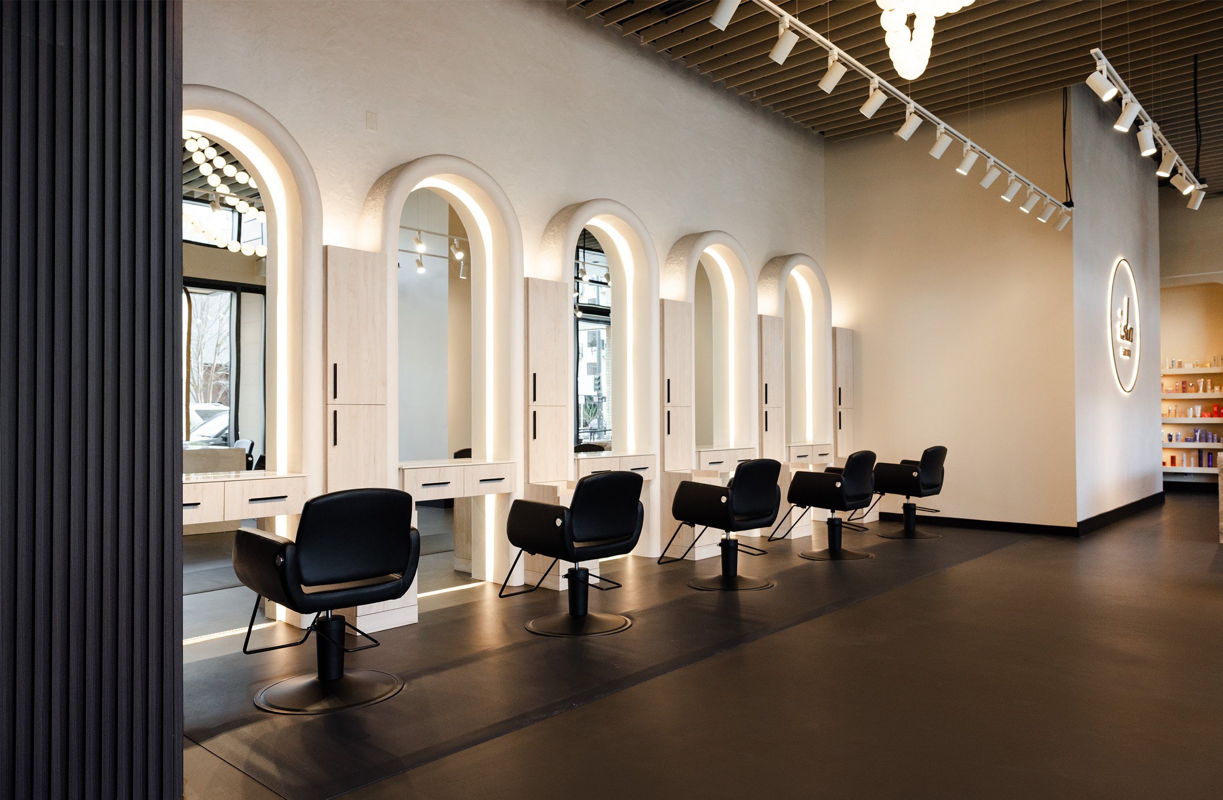 Intérieur épuré du salon Maison Nuance, arches en bois clair et miroirs rétroéclairés
